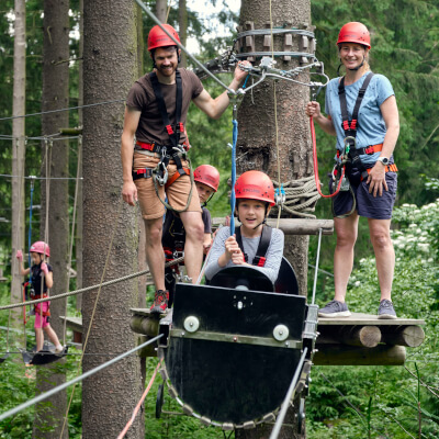 Eine Familie klettert durch den Hochseilgarten